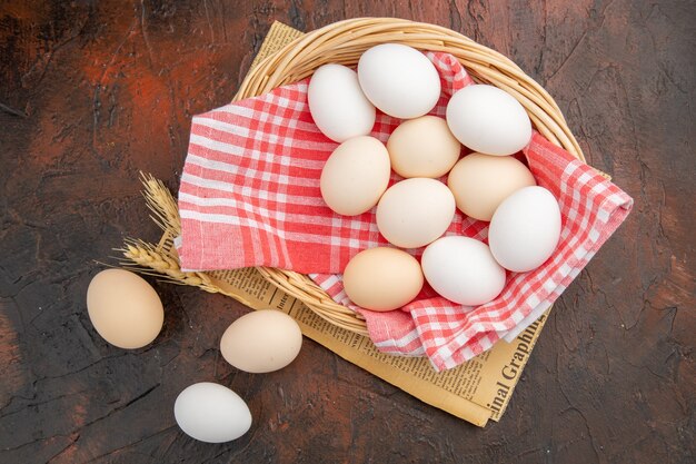 Top view white chicken eggs inside basket on dark table