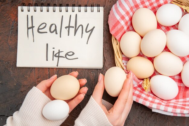 Top view white chicken eggs inside basket with towel on dark table