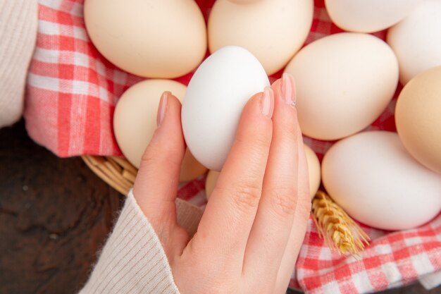 Top view white chicken eggs inside basket with towel on dark table