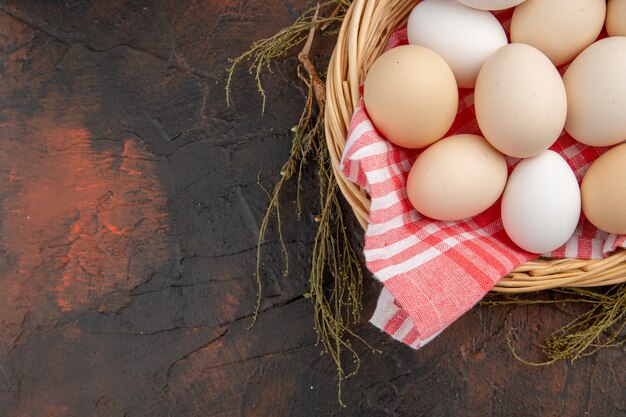 Top view white chicken eggs inside basket with towel on dark table