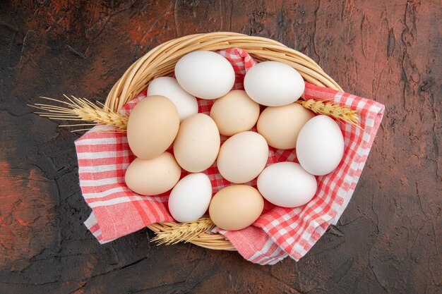 Top view white chicken eggs inside basket with towel on dark table