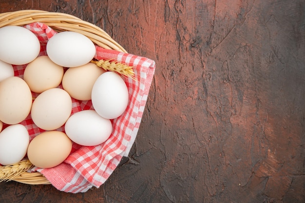 無料写真 暗いテーブルの上のタオルとバスケットの中の白い鶏卵の上面図