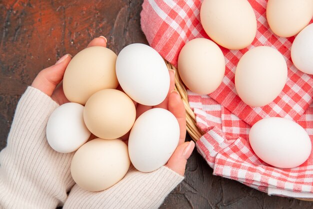 Top view white chicken eggs inside female hands on dark table