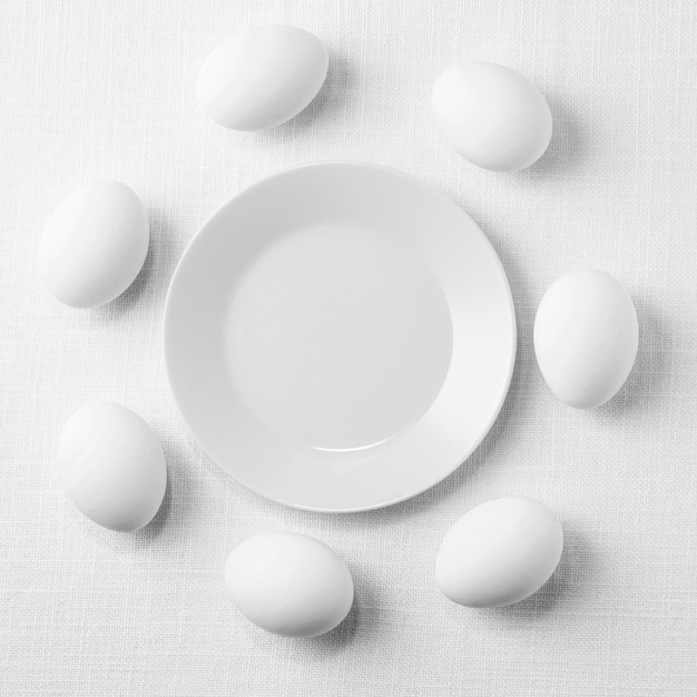 Вид сверху белые куриные яйца на столе с тарелкой