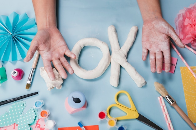 Top view of white clay letter between messy hand