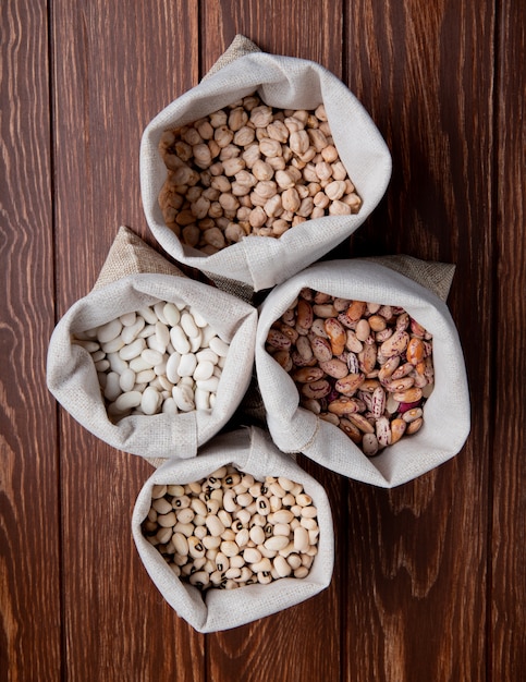 Free photo top view white and colored beans with peas in burlap bags