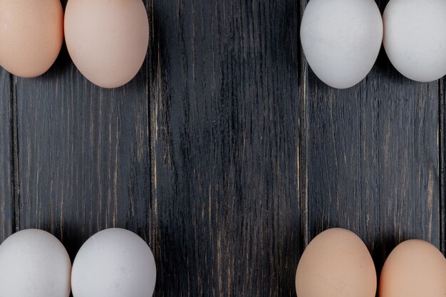 Top view of white and cream colored eggs on a wooden background with copy space