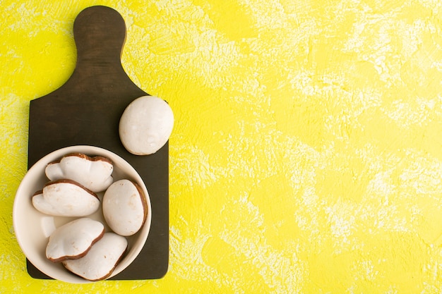 Free photo top view of white delicious cookies isolated on the yellow surface