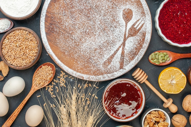 Vista dall'alto farina bianca a forma di forchetta e cucchiaio con uova e noci su una torta scura dolce dessert biscotto zucchero pasticceria torta tè