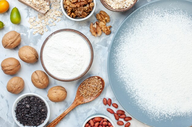 Vista dall'alto farina bianca all'interno del piatto con semi di noci e uova su pasta di noci bianche cuocere la gelatina di torta di frutta con foto a colori per alimenti