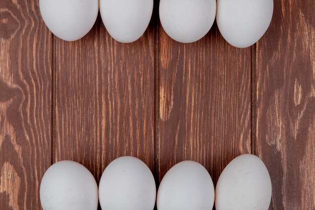 Top view of white fresh chicken eggs on a wooden background with copy space