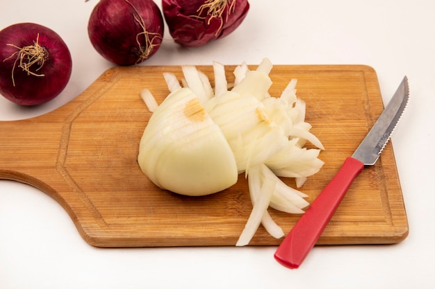 Top view of white onion on a wooden kitchen board with knife with red onions isolated on a white surface