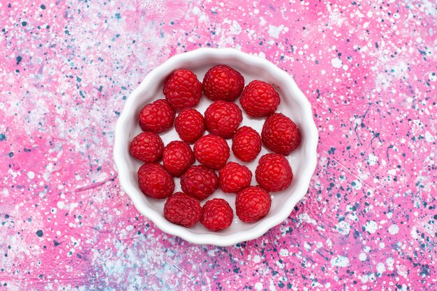 Top view white plate with cleaned raspberries on the pink background berry fruit color sugar sour