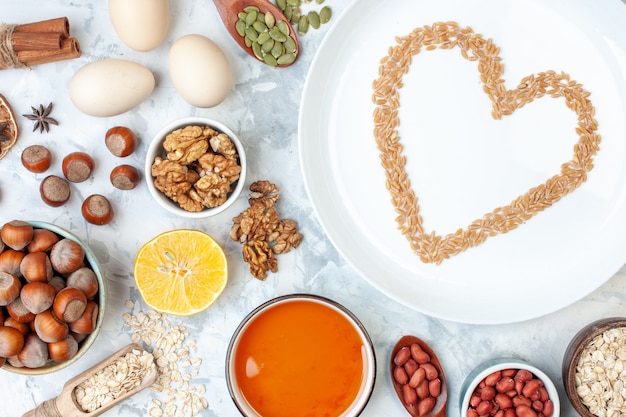 Free photo top view white plate with jelly eggs different nuts and seeds on white dough color cake sweet sugar pie nut heart