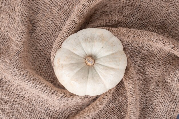 Top view of white pumpkin on burlap.