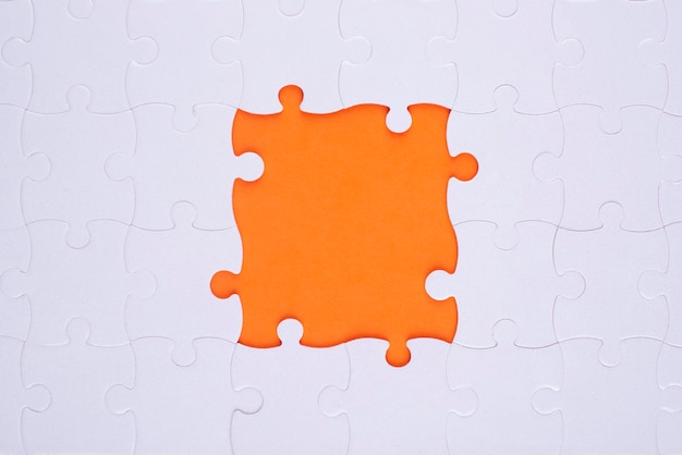 Pezzi di puzzle bianchi vista dall'alto e sfondo arancione