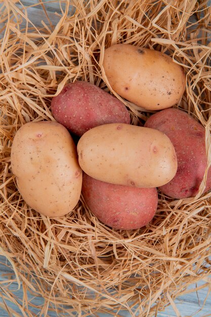 Top view of white and red potatoes in nest on wooden surface