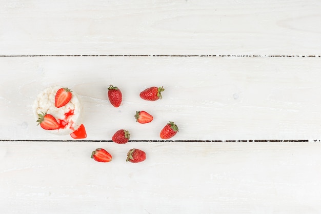 Top view white rice cakes with strawberries on white wooden board surface. horizontal