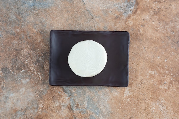 Free photo top view of white round cheese on dark plate on marble