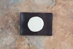 Free photo top view of white round cheese on dark plate on marble