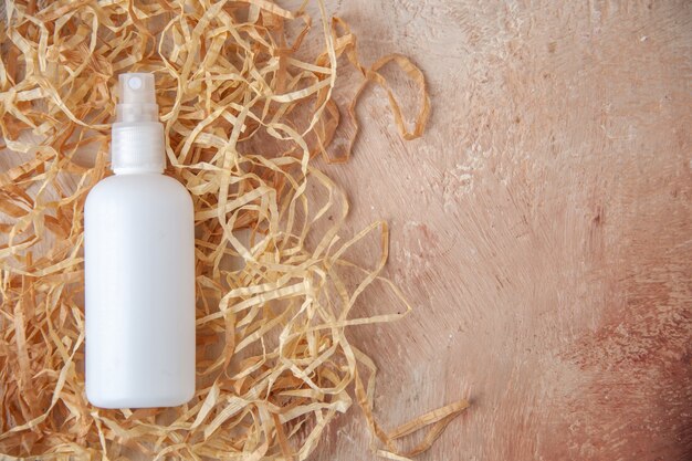 Top view white spray bottle on nude background