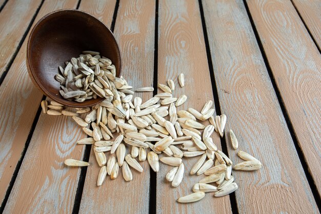 Top view of white sunflower seeds scattered from a wooden pot