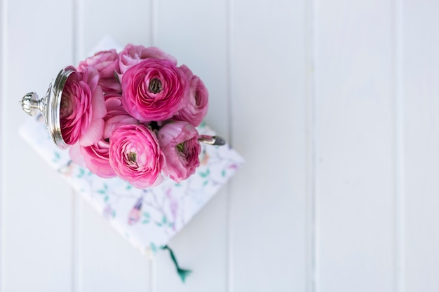 Top view of white surface with pink flowers and book