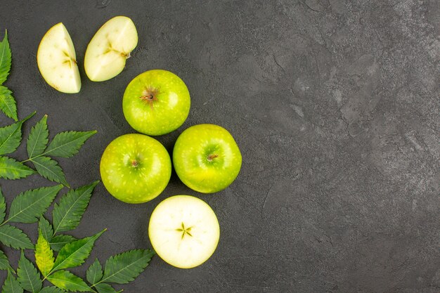 Top view of whole and chopped fresh green apples and mint on black background