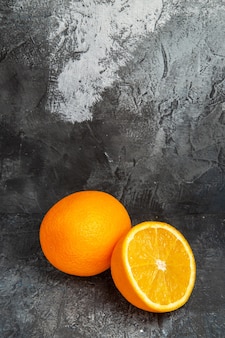 Vista dall'alto di arance fresche intere e tagliate a metà su sfondo grigio