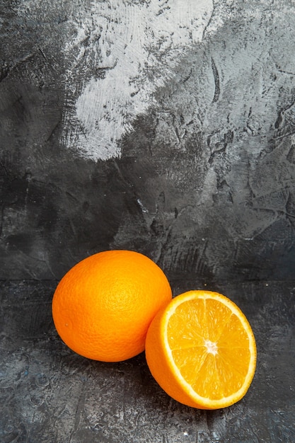 Top view of whole and cut in half fresh oranges on gray background