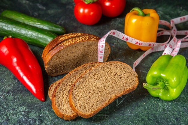 Top view of whole fresh organic vegetables and meter black bread slices on mix colors surface