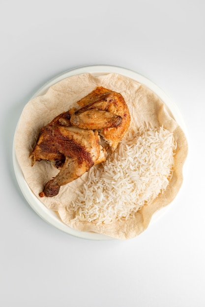 Top view of whole grilled chicken and rice served on flatbread