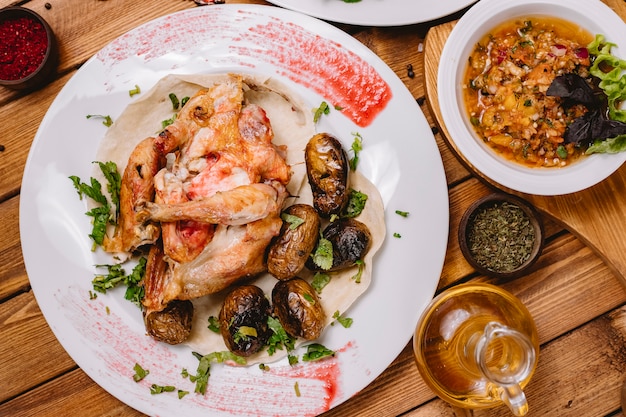 Top view of whole grilled chicken served with grilled potatoes