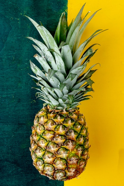 Top view of whole pineapple on green and yellow surface