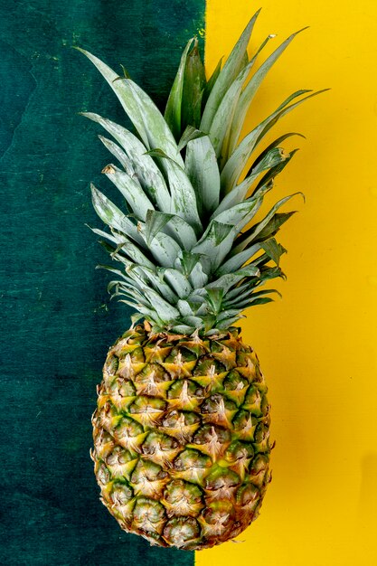 Top view of whole pineapple on green and yellow surface