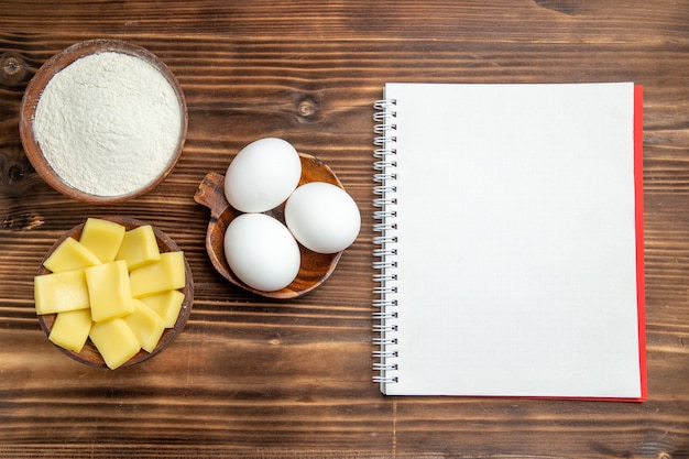 Top view whole raw eggs with flour and cheese on brown table egg dough flour dust products