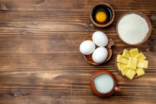 갈색 테이블 계란 반죽 밀가루 먼지 제품에 밀가루 우유와 치즈와 함께 상위 뷰 전체 원시 계란