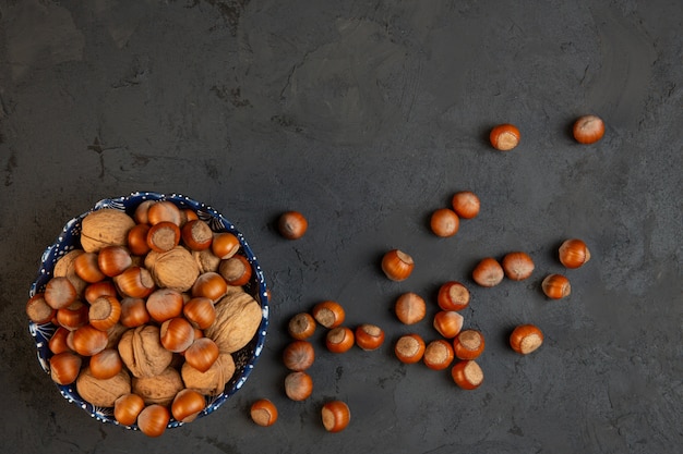 Free photo top view of whole walnuts and hazelnuts in a bowl on dark j