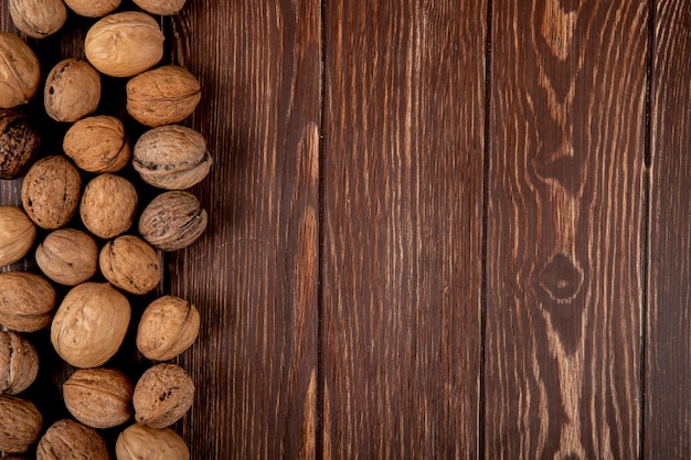 Foto gratuita la vista superiore di intere noci ha sparso su fondo di legno con lo spazio della copia