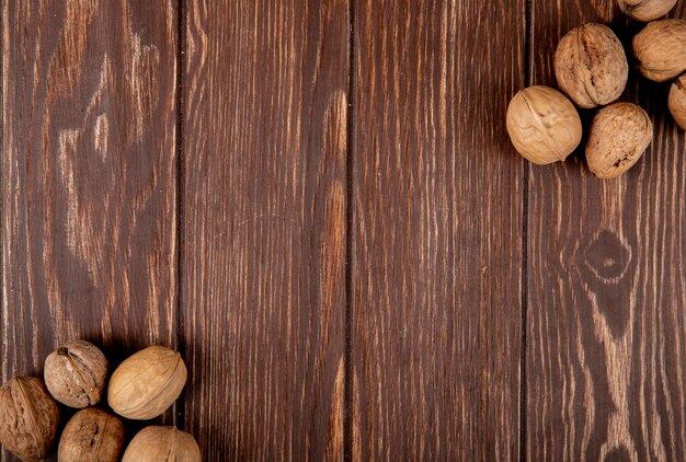 Top view of whole walnuts scattered on wooden background with copy space