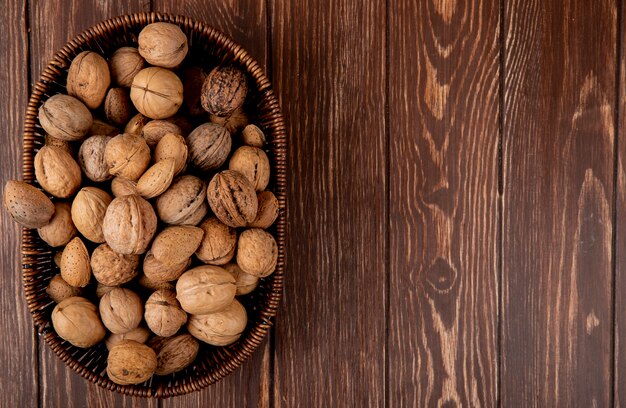 Top view of whole walnuts in a wicker basket on wooden background with copy space