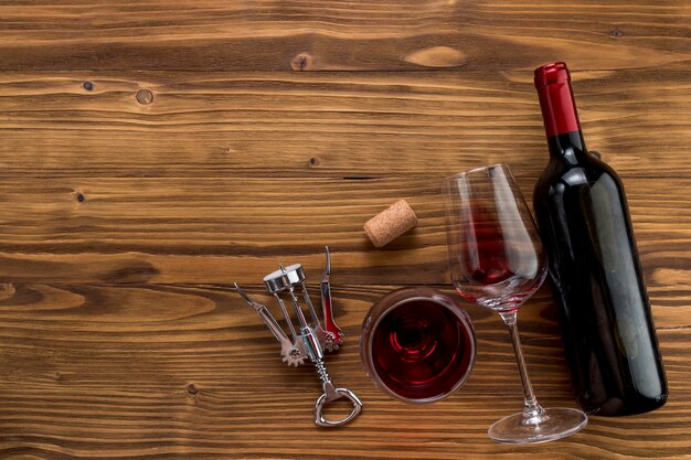 Вид сверху бутылка вина с бокалом на деревянном фоне