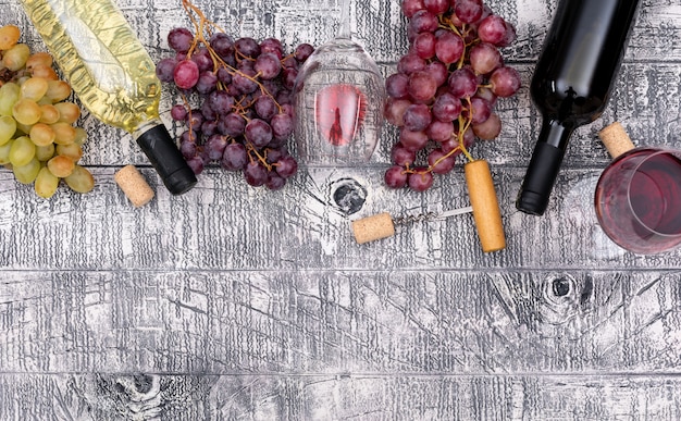 Вид сверху винные бутылки с виноградом и копией пространства на белой деревянной горизонтали