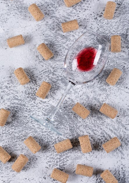 Top view of wine glass with cork stoppers on white stone  vertical