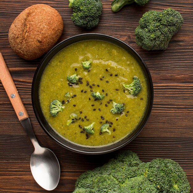 Top view of winter broccoli soup in bowl with bread and spoon