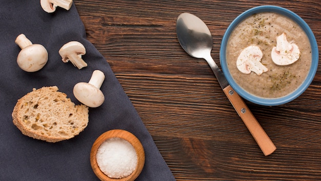 Top view of winter mushroom soup in bowl with spoon and bread