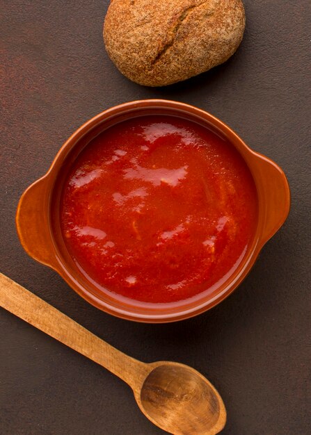 Top view of winter tomato soup in bowl with bread and spoon