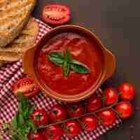 Foto gratuita vista dall'alto della zuppa di pomodoro invernale nella ciotola con pane tostato e tovaglia