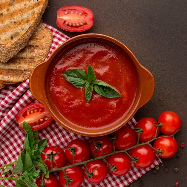 Top view of winter tomato soup in bowl with toast and tablecloth