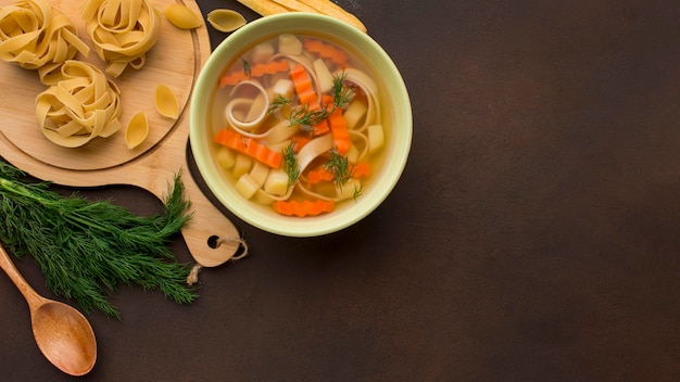 Top view of winter vegetables soup in bowl with copy space and tagliatelle